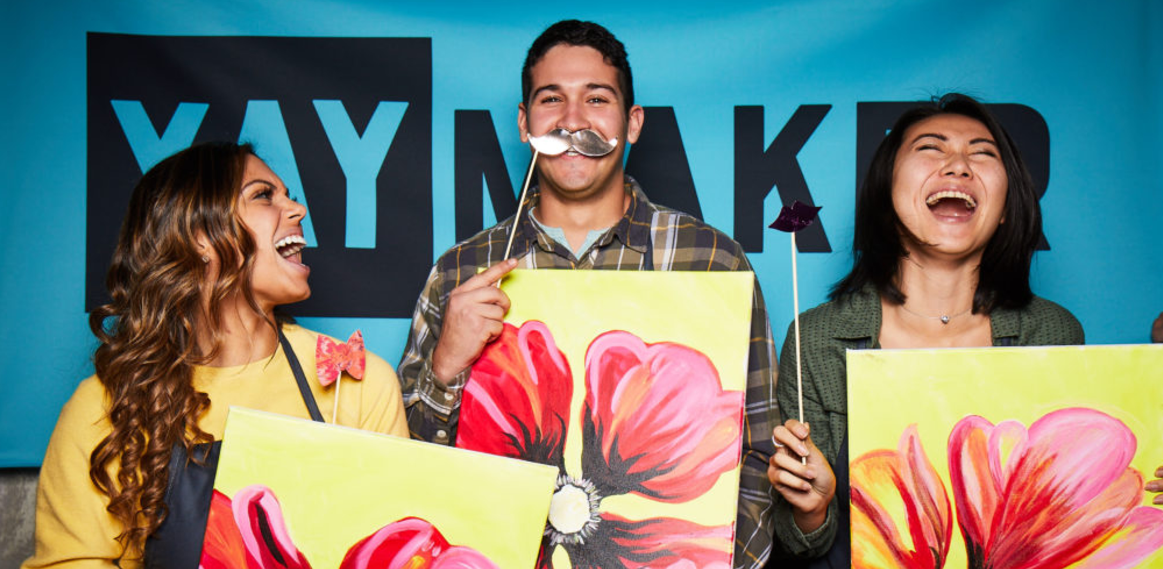 Three people laughing while having their photo taken in Paint Night